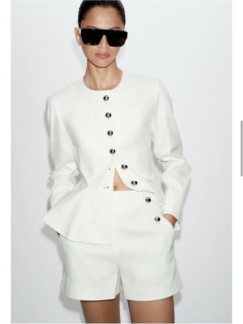 Tailored white shorts with decorative buttons.